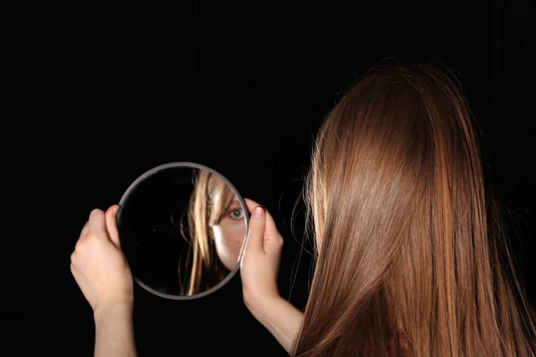 Woman looks at herself in a handheld mirror.