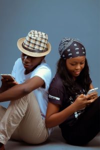 man and woman sitting while using cellphones