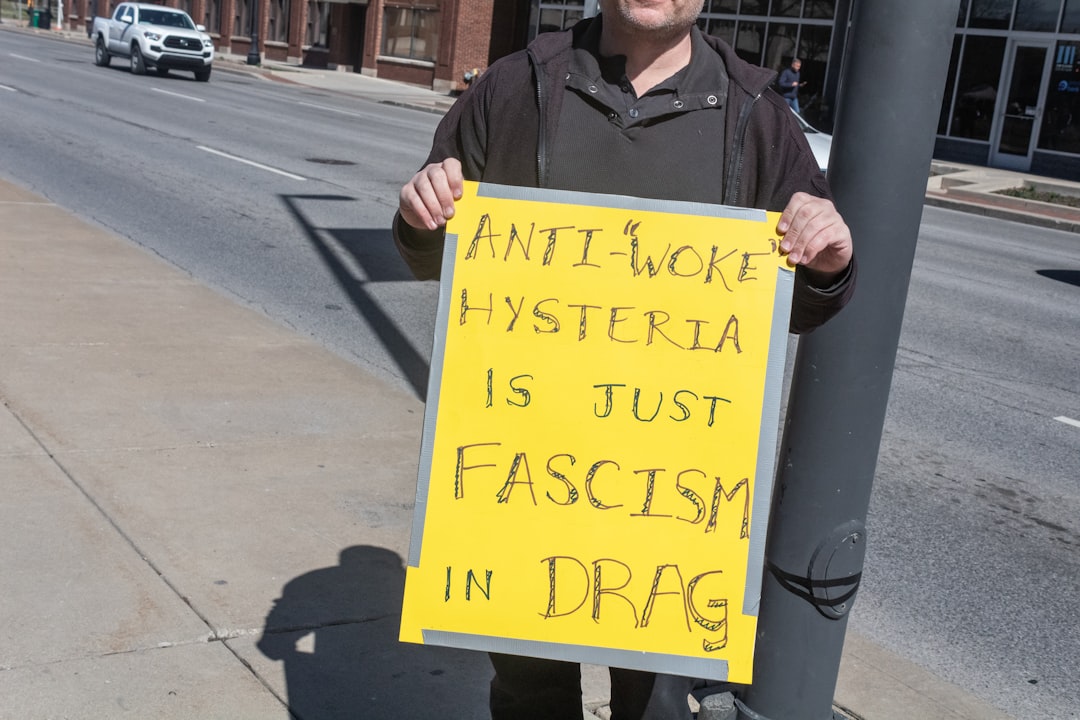 a man holding a sign that says anti - more hyperia is just fasc
