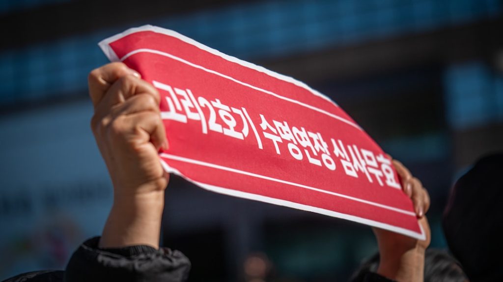 Hands hold a red sign with korean text