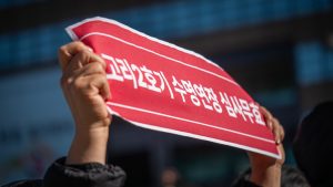 Hands hold a red sign with korean text