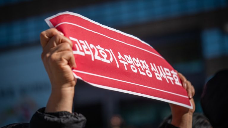 Hands hold a red sign with korean text