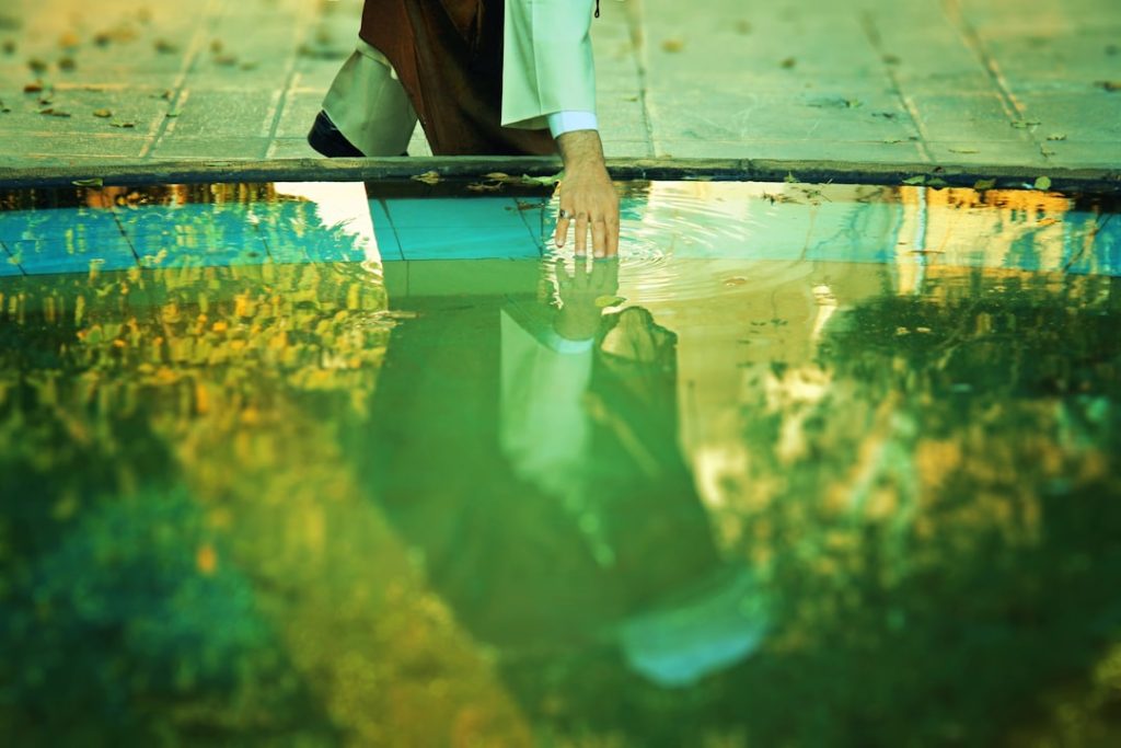 a man kneeling down next to a pool of water
