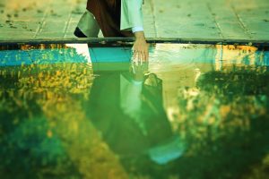 a man kneeling down next to a pool of water