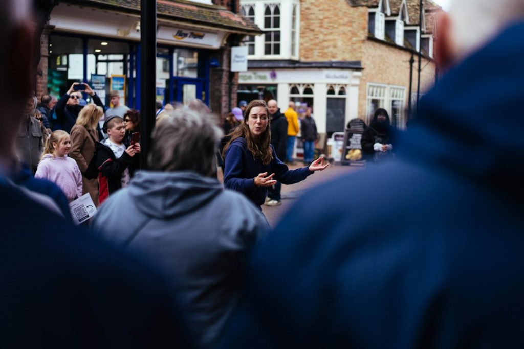 A woman speaks to a crowd on a street