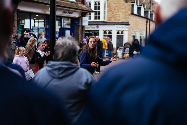 A woman speaks to a crowd on a street