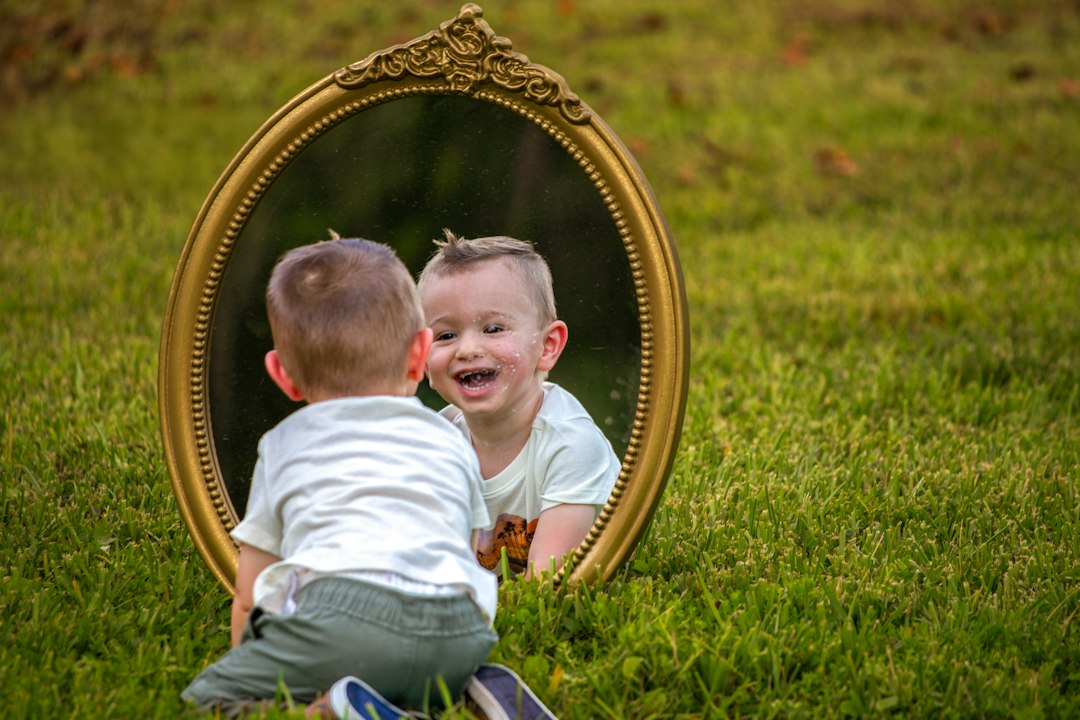 A baby smiles at their reflection in a mirror